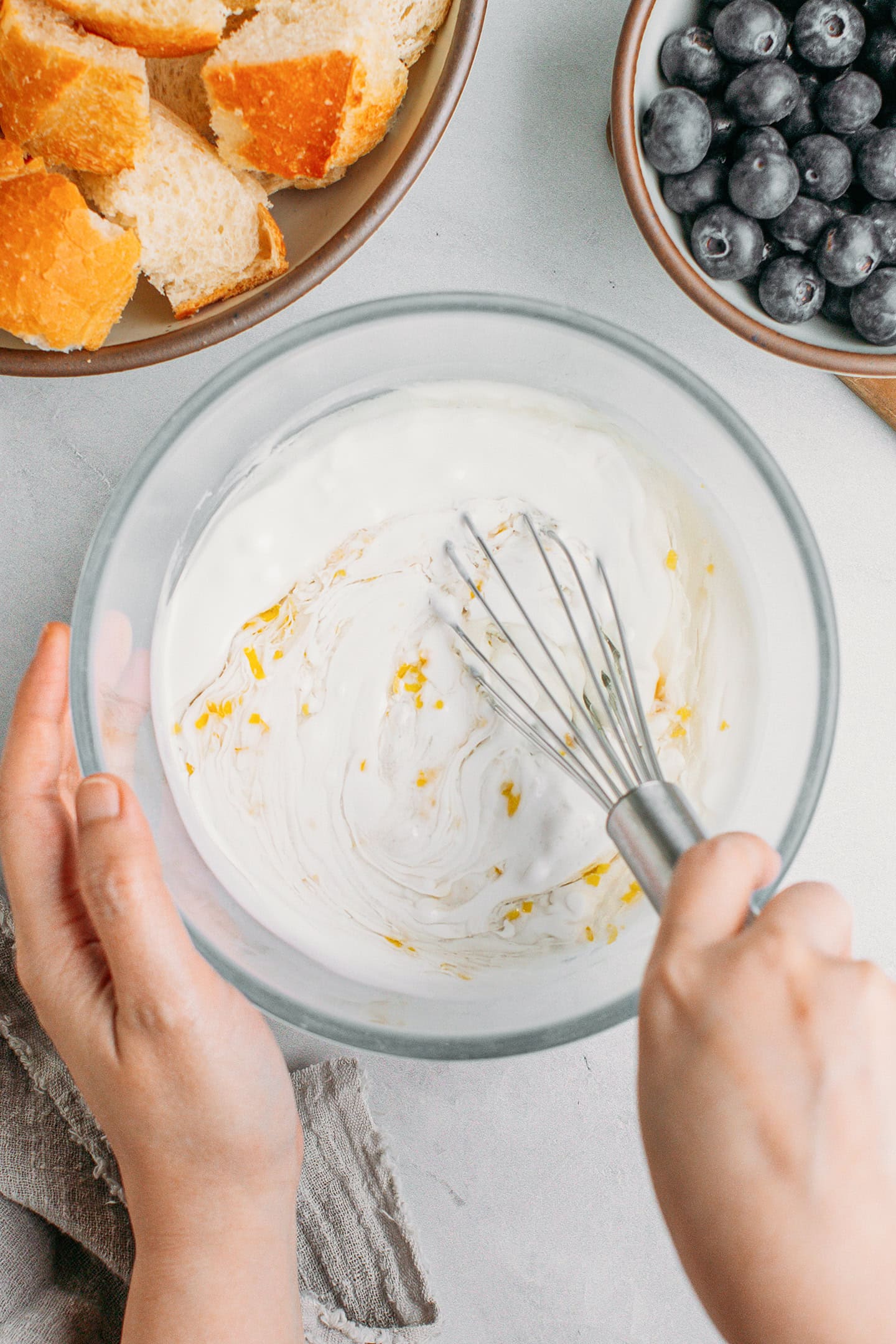 Whisking coconut milk with sugar and lemon zest in a bowl.