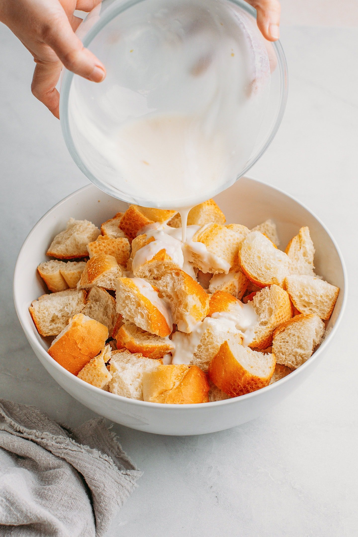 Pouring sweet coconut milk over diced bread.