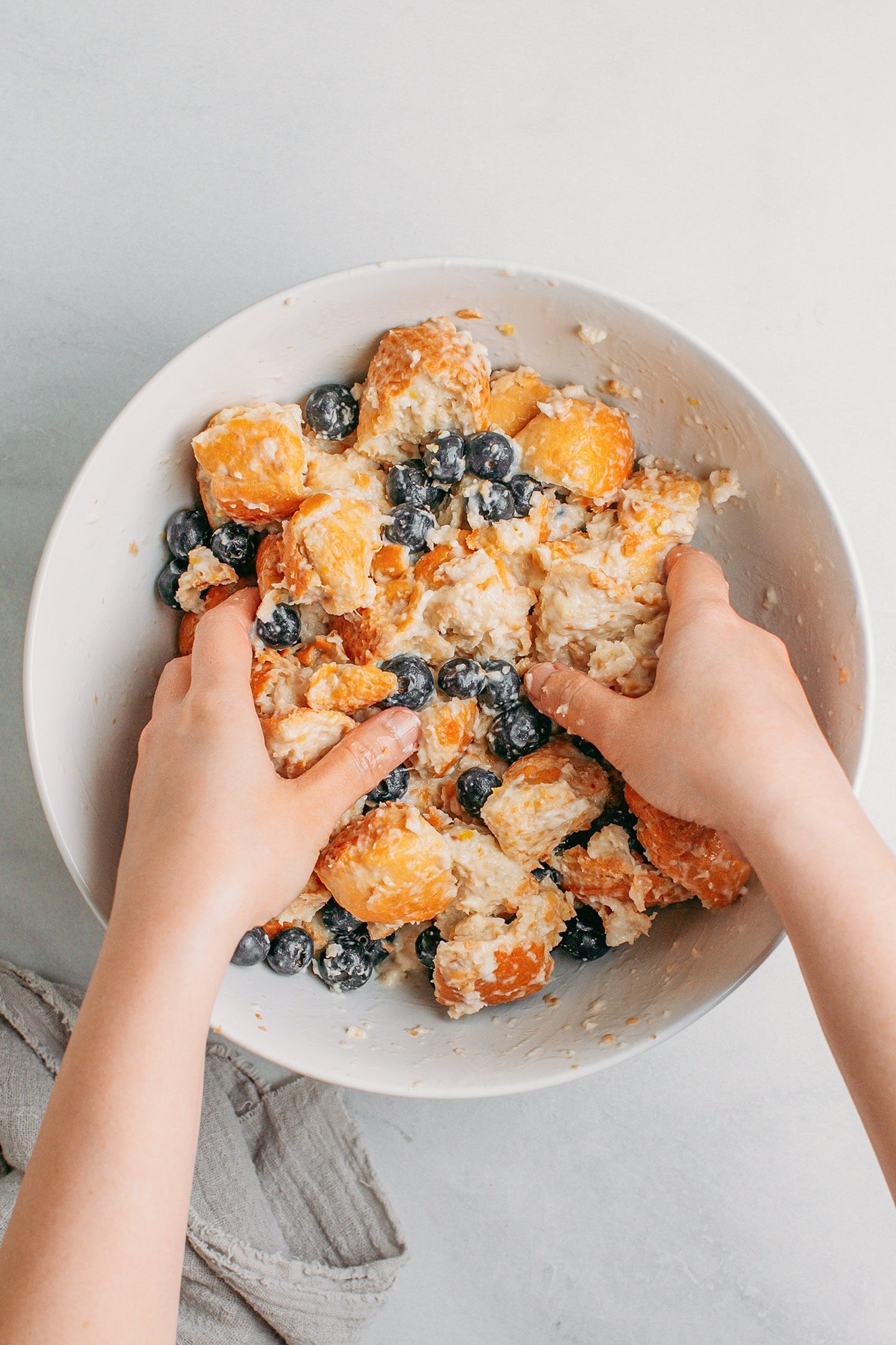 Mixing fresh blueberries with diced bread.