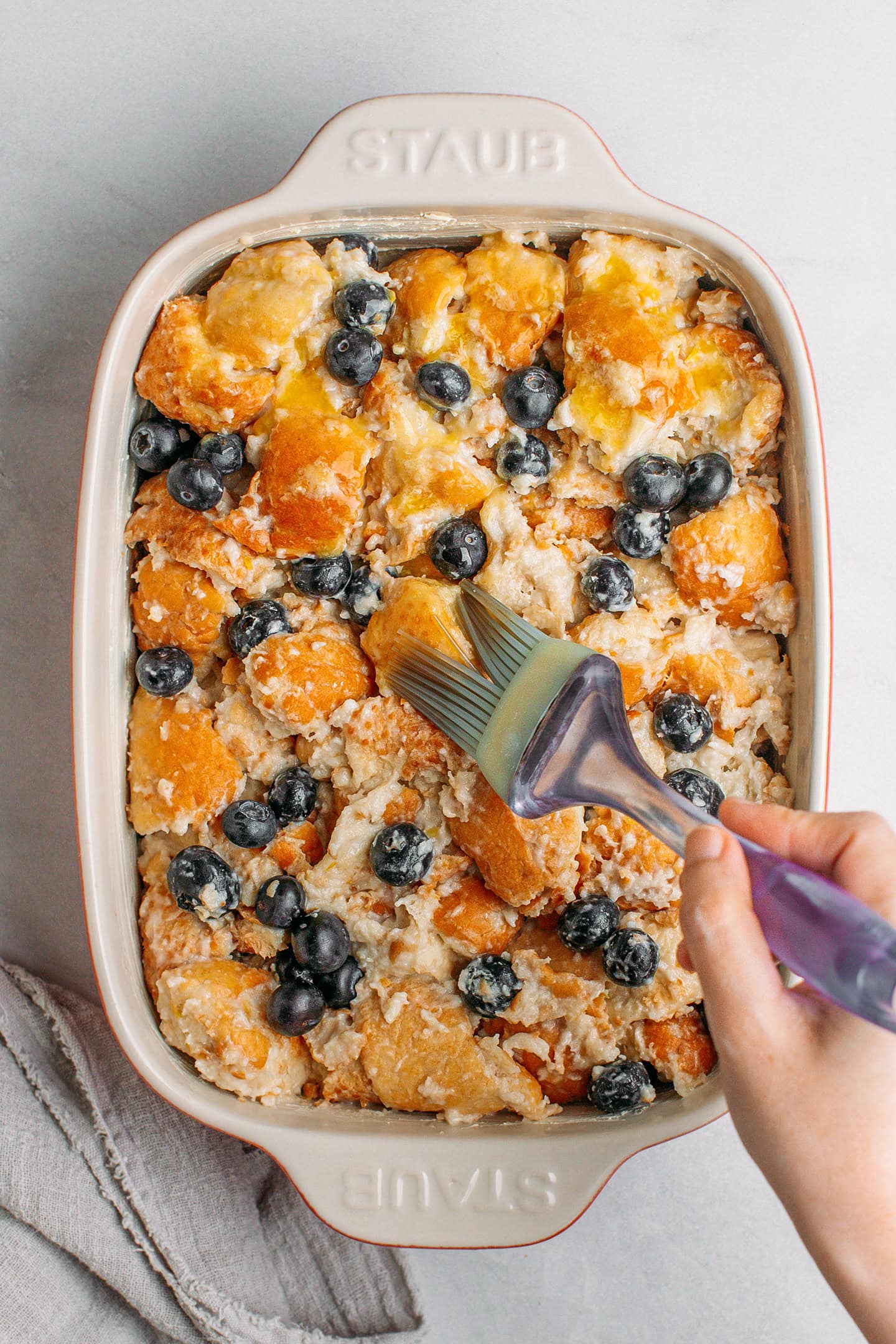 Brushing melted butter on top of bread pudding.