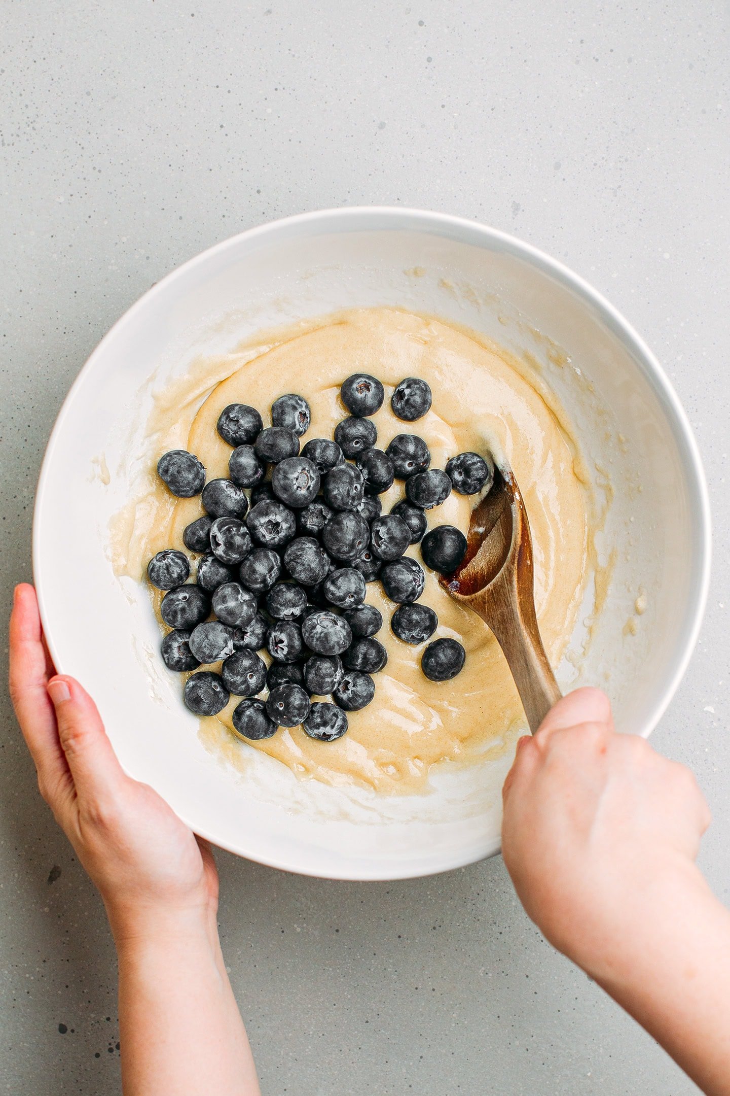 Fresh blueberries and muffin batter in a mixing bowl.
