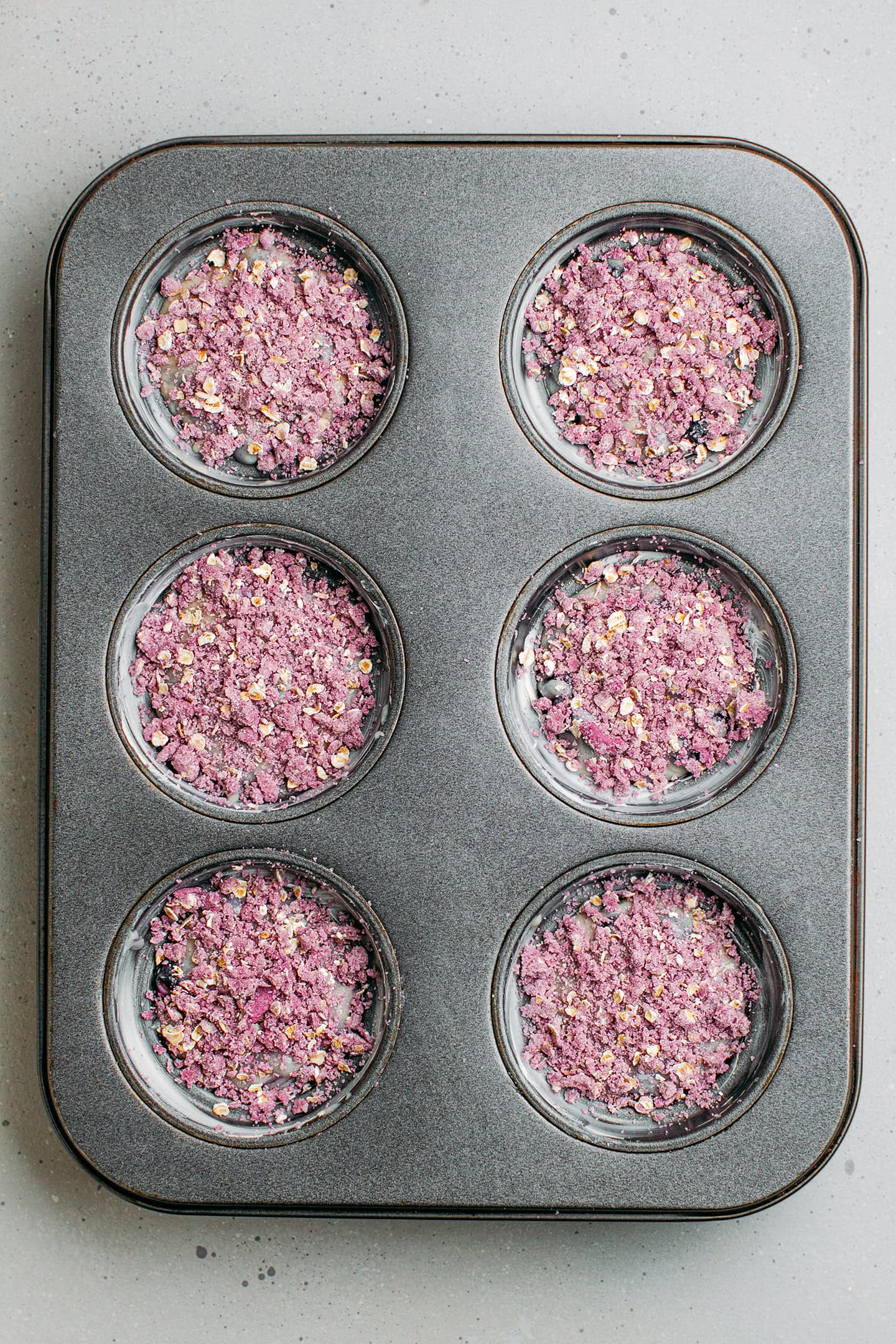 Unbaked blueberry muffins in a pan.