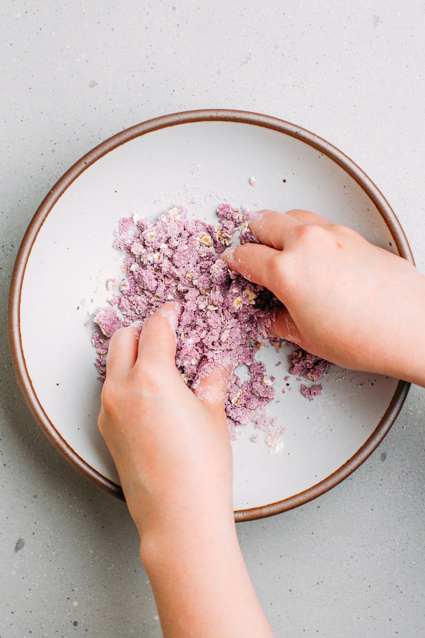 Mixing flour, butter, and ube powder in a bowl.
