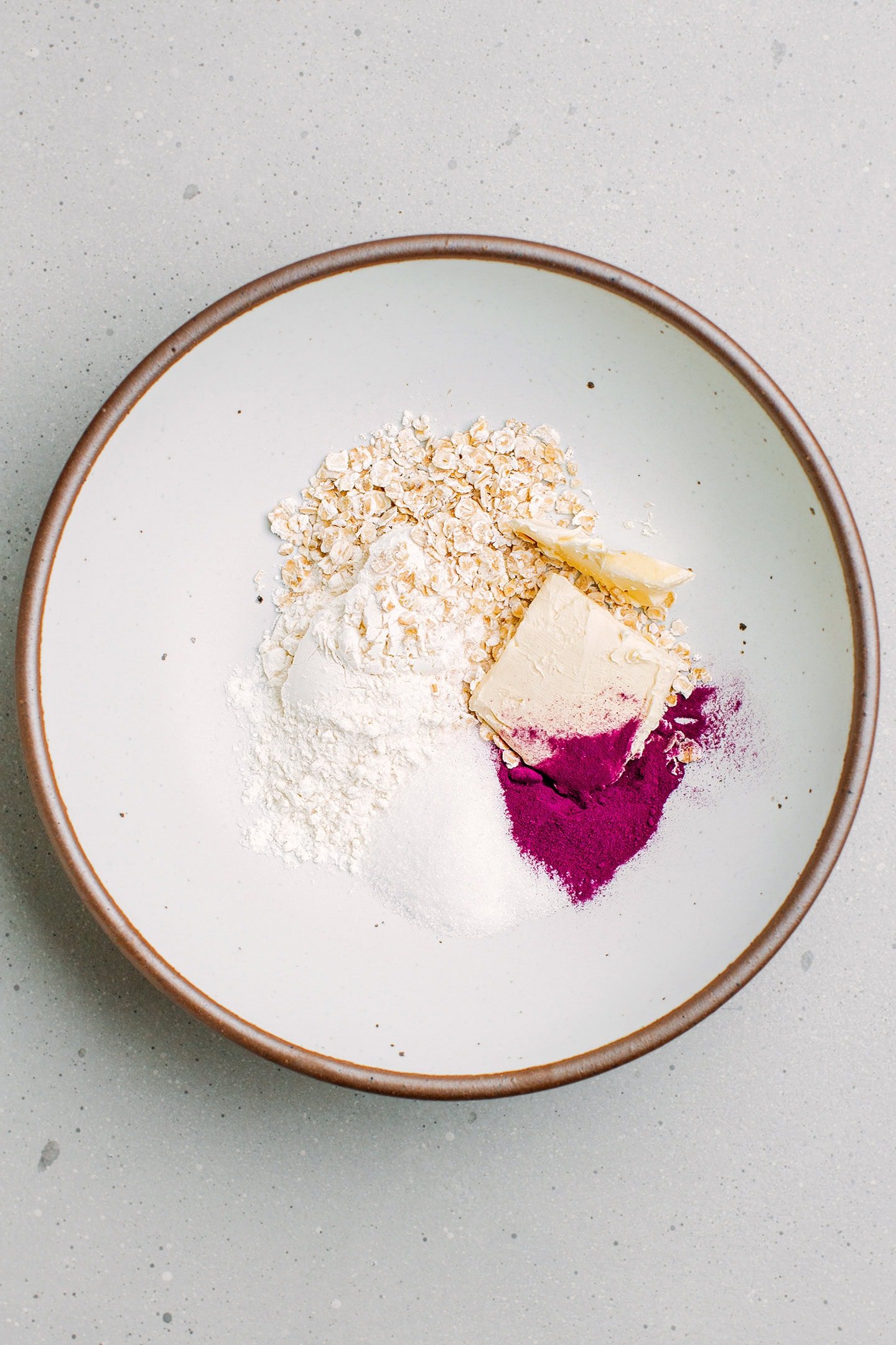 Flour, oats, butter, and ube powder in a bowl.