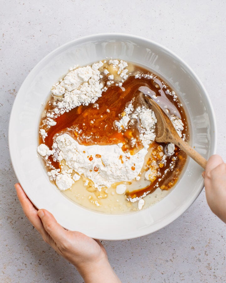 Mixing caramel sauce and oil with flour in a mixing bowl.
