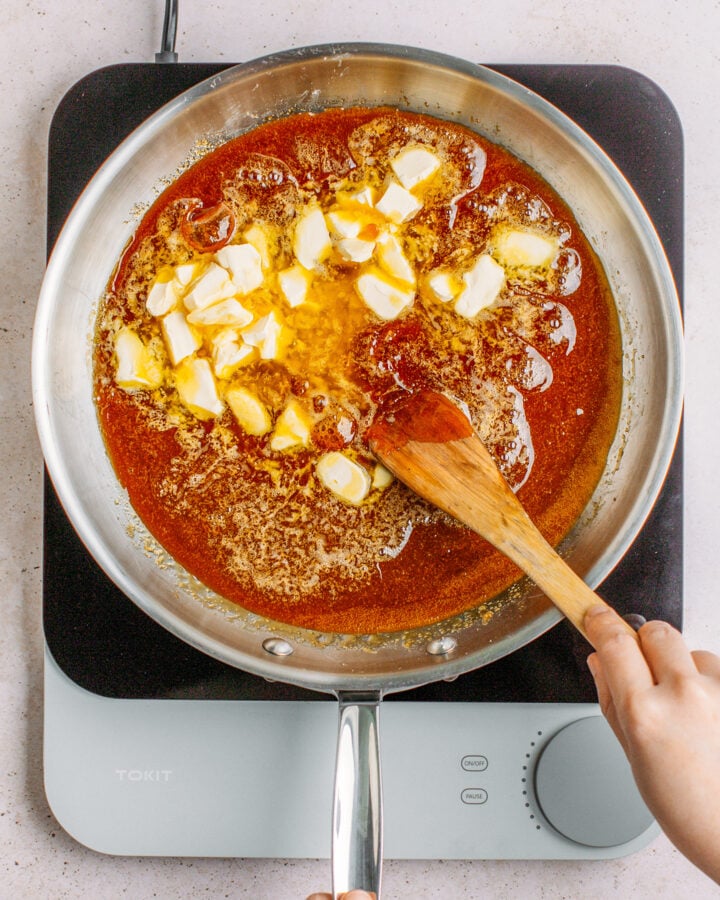 Stirring butter into caramel in a large pan.