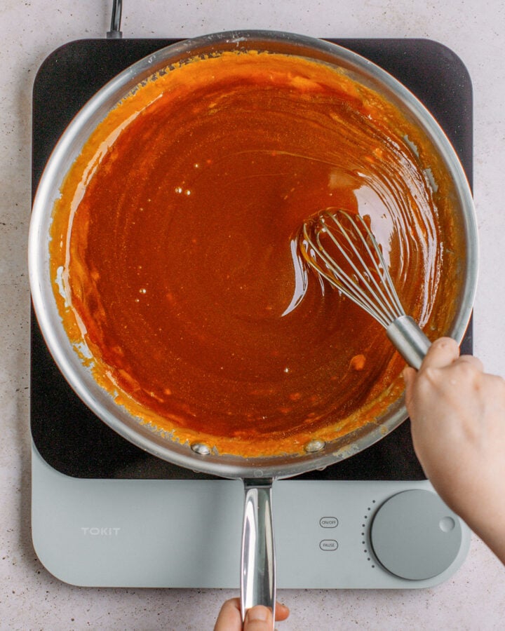 Whisking caramel sauce in a large pan.
