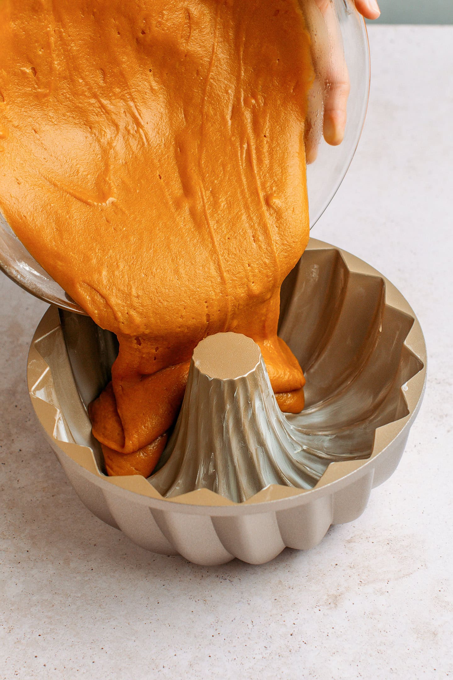 Pouring caramel pound cake batter into a bundt cake pan.
