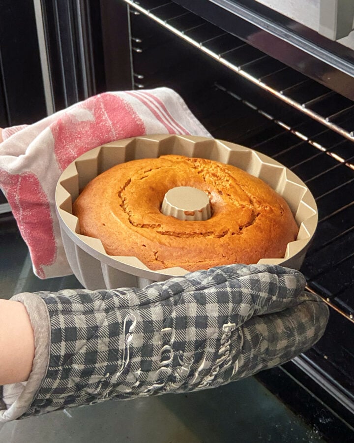 Removing a baked caramel bundt cake from the oven.