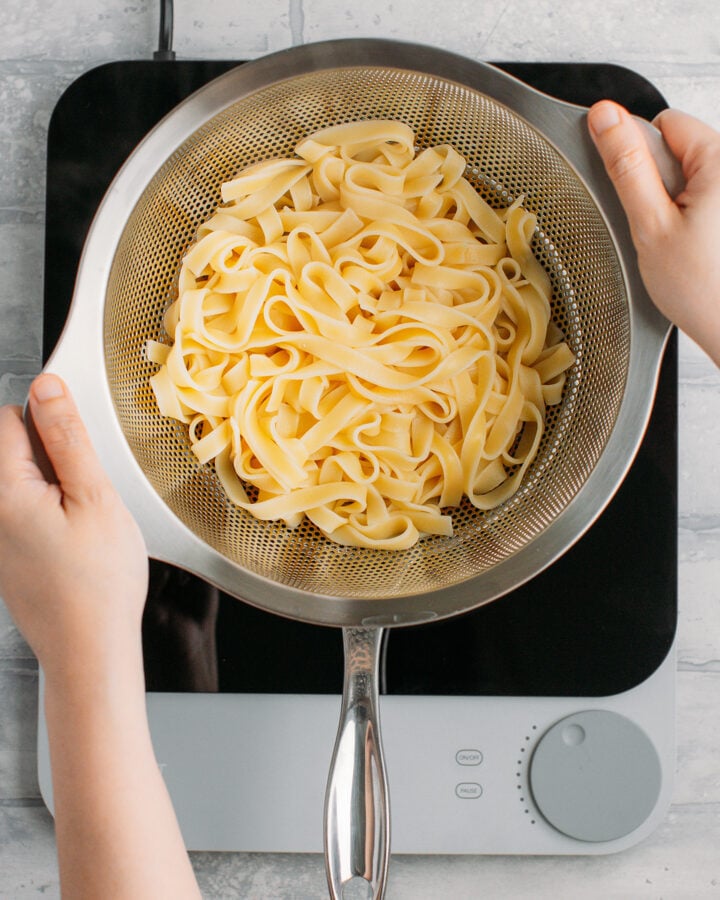 Draining cooked tagliatelle pasta.