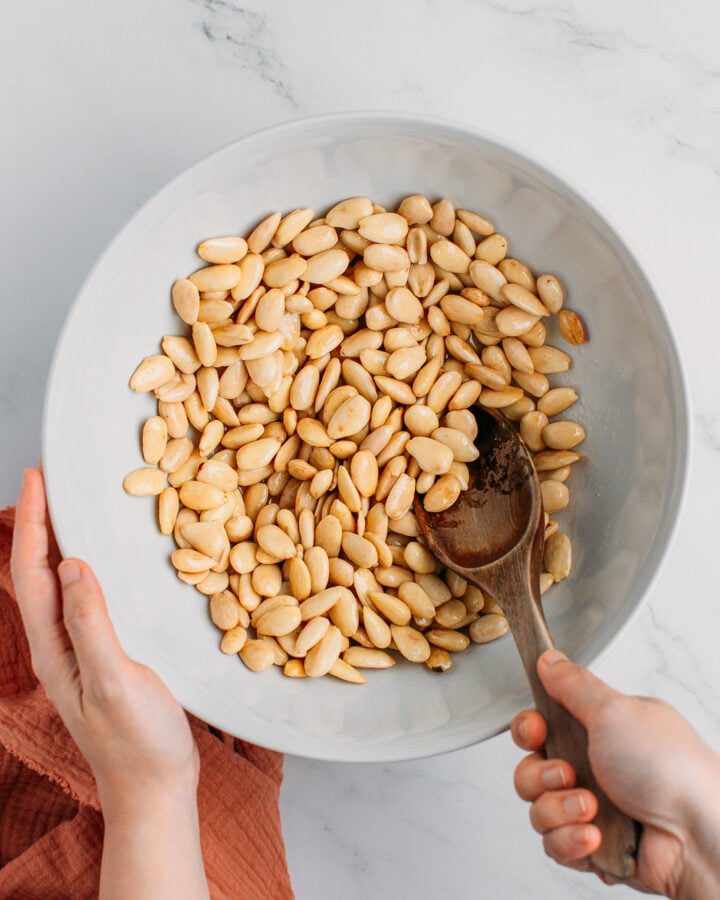 Tossing almonds with maple syrup and oil.
