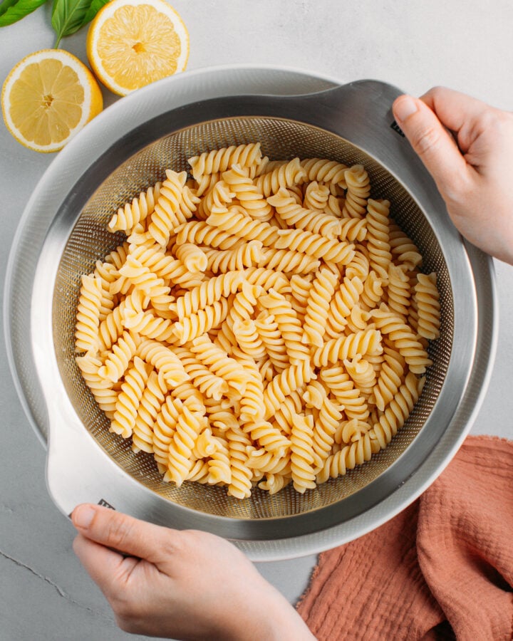 Draining fusilli pasta using a large sieve.