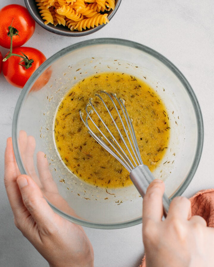 Whisking vinaigrette dressing in a small bowl.