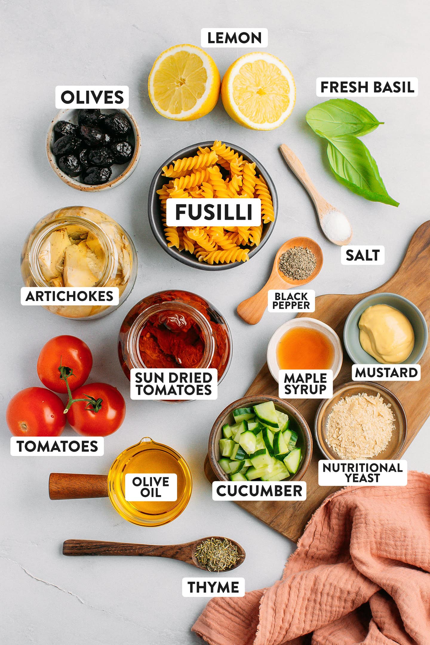 Ingredients like fusilli pasta, artichoke hearts, sun-dried tomatoes, and fresh basil.