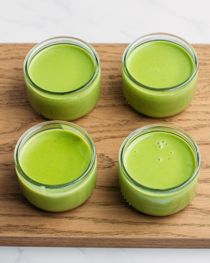 Four glass ramekins filled with matcha panna cotta.