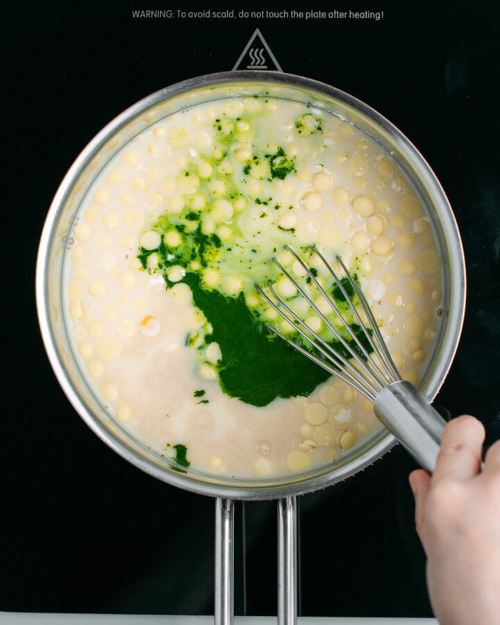Whisking matcha with milk and cocoa butter in a saucepan.