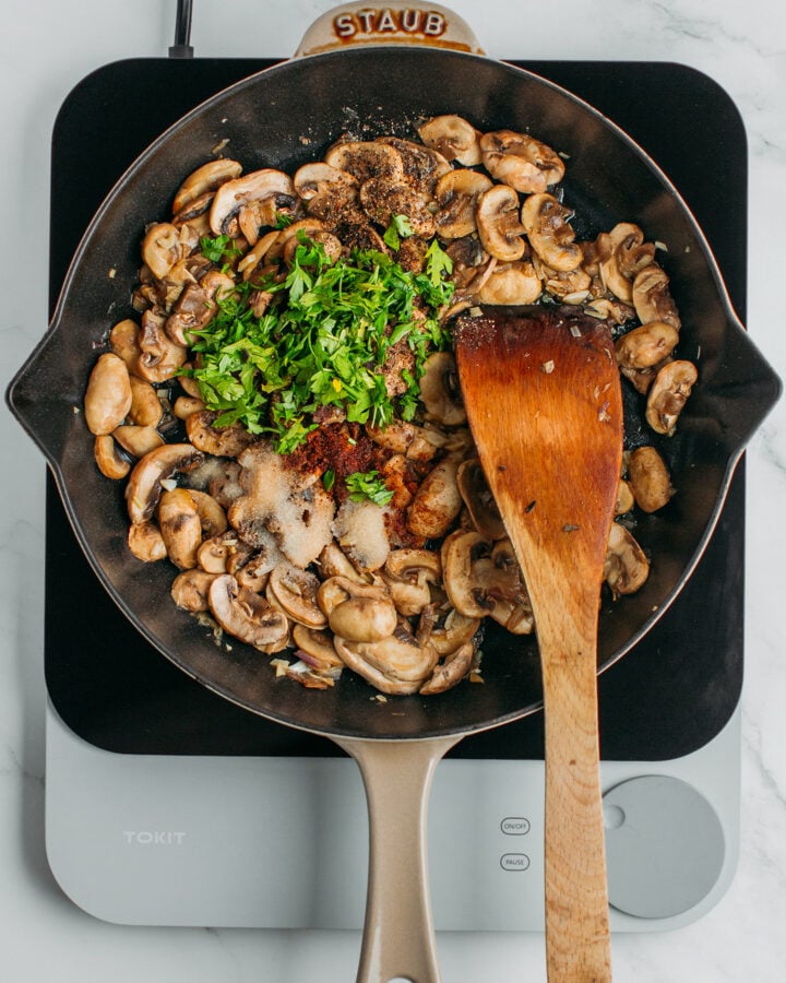 Sautéed mushrooms and parsley in a skillet.