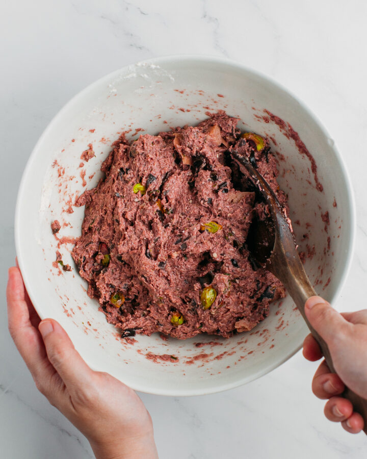 Mixing mushroom paste with pistachios, vegan bologna, and black mushrooms.