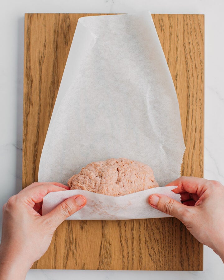 Rolling a roll of seitan in a sheet of parchment paper.