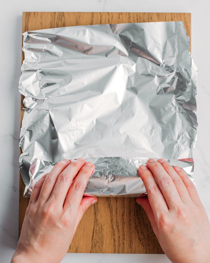 Rolling a log of seitan in aluminum foil.