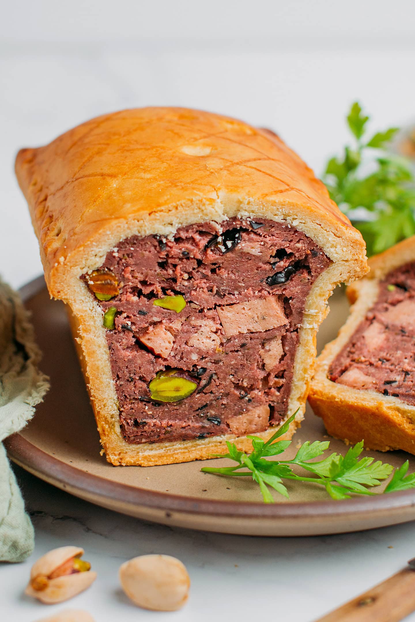 Vegan terrine pie filled with pistachios, vegan bologna, and wood ear mushrooms on a small plate.