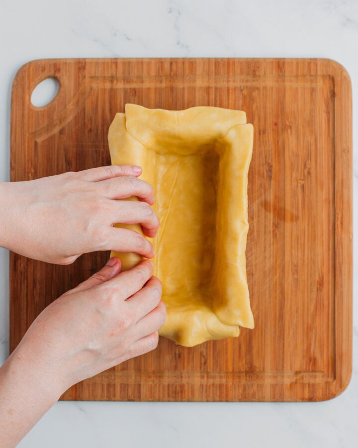 Pressing a pie crust into a rectangle baking pan.