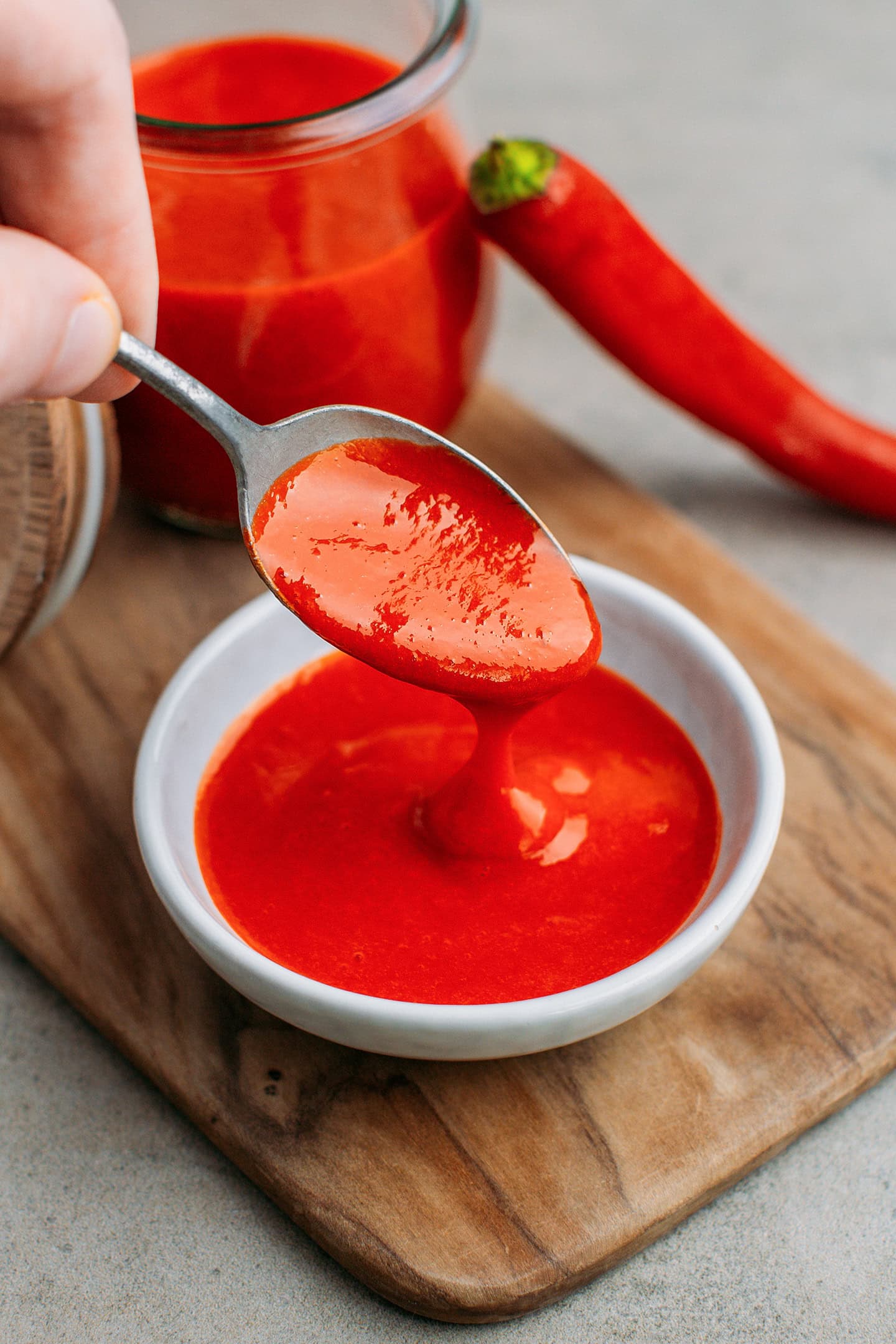 Using a spoon to show the consistency of homemade buffalo sauce.