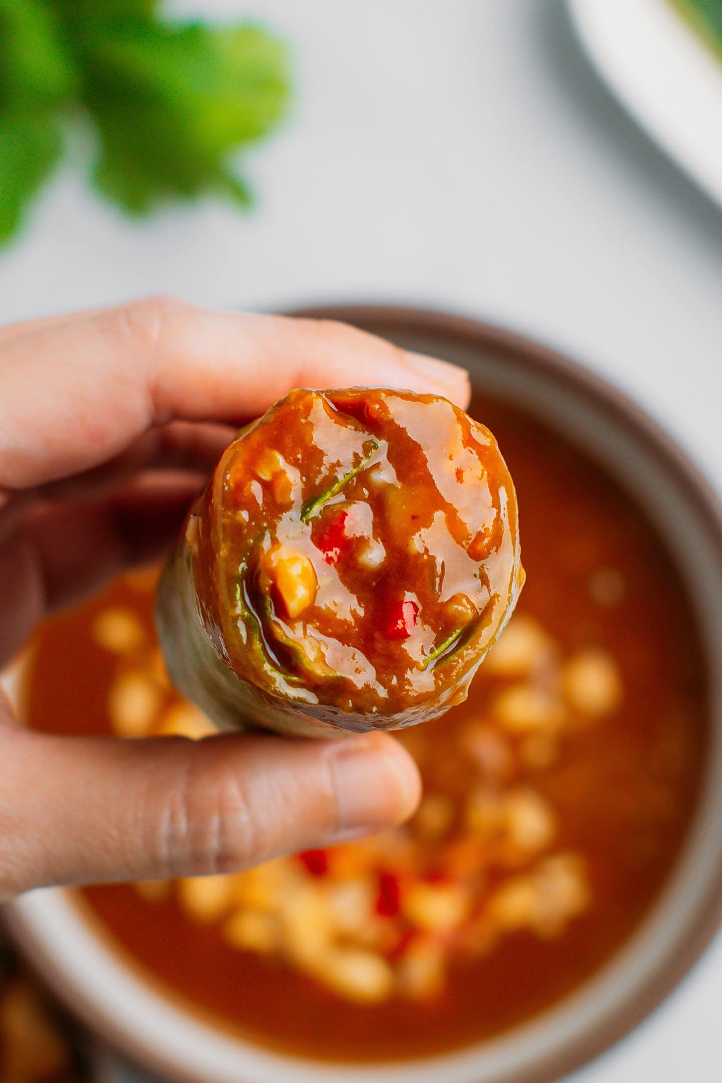 Holding a fresh spring roll dipped in peanut sauce.
