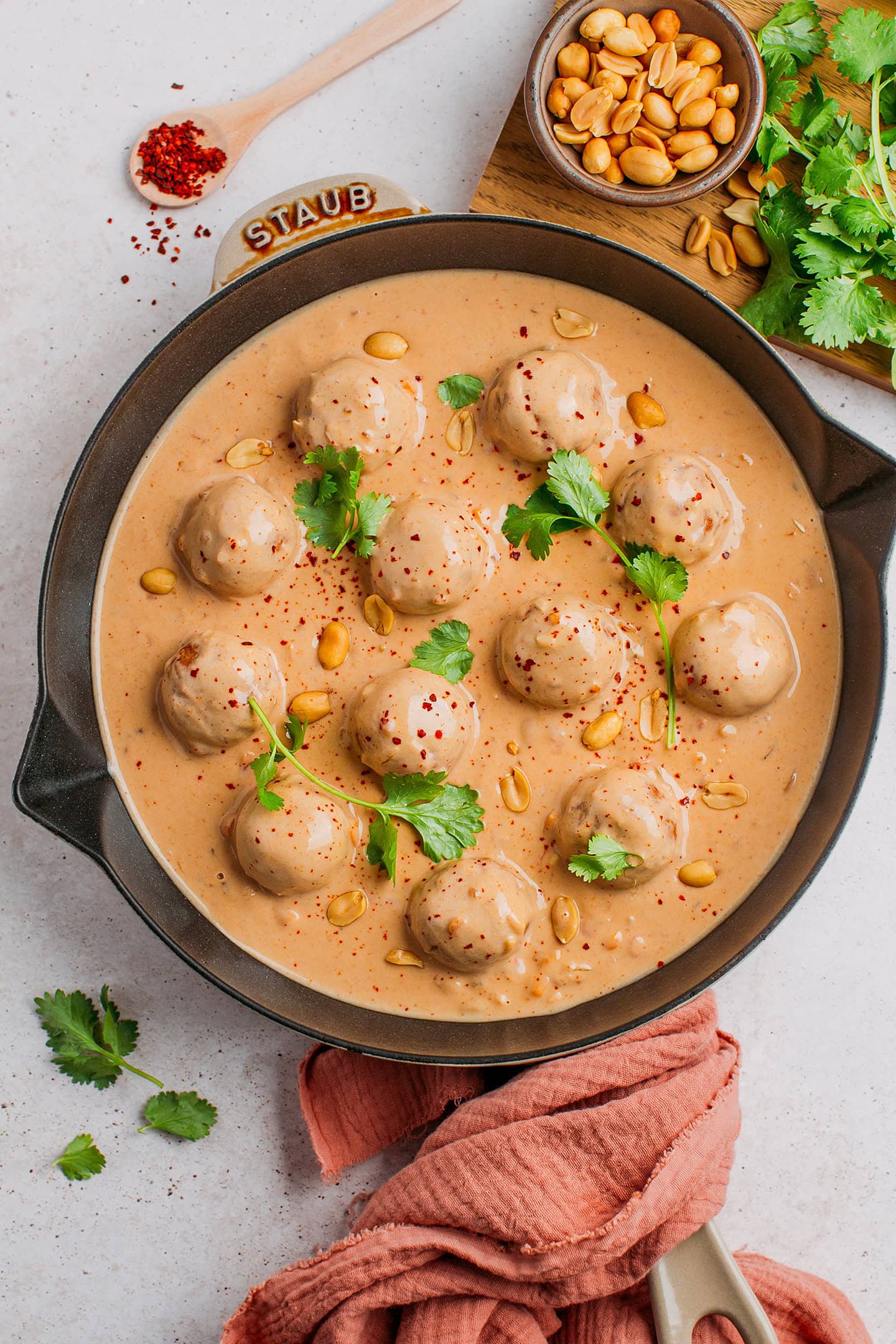 Fonio balls and peanut butter sauce topped with fresh cilantro in a skillet.