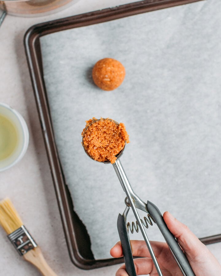 Scooping some fonio mixture using a cookie scoop.