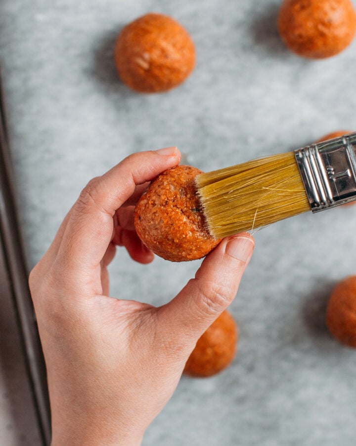 Brushing oil on a fonio ball using a pastry brush.