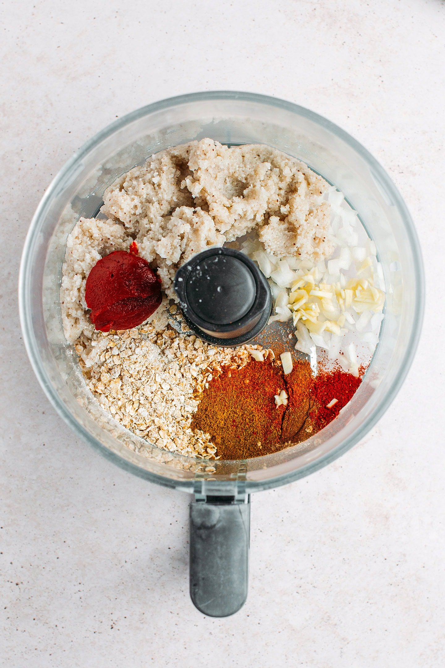 Cooked fonio, quick oats, tomato paste, and spices in a food processor.