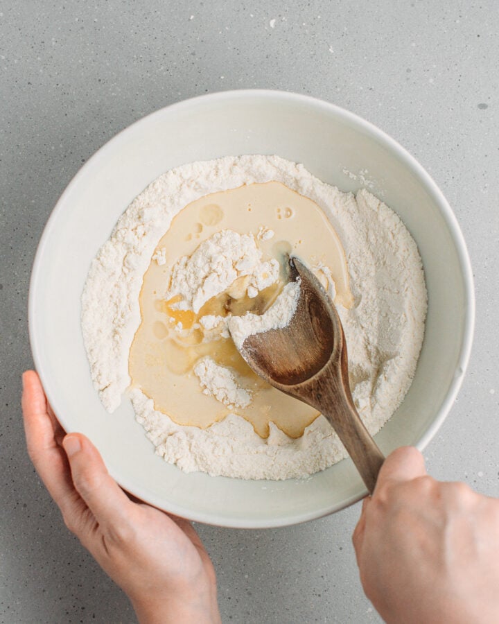 Mixing flour, sugar, plant-based milk, and oil in a bowl.
