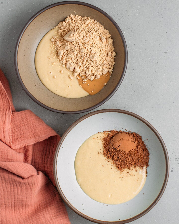 Two bowls containing two batters, one with peanut butter and the other with cocoa powder.