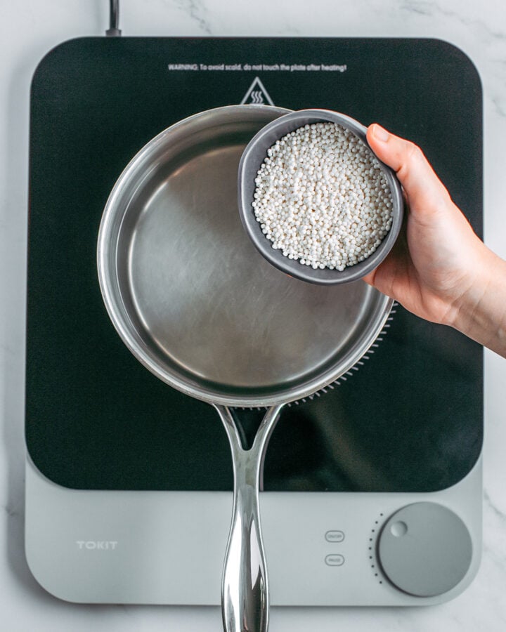 Pouring tapioca pearls into a pot of boiling water.