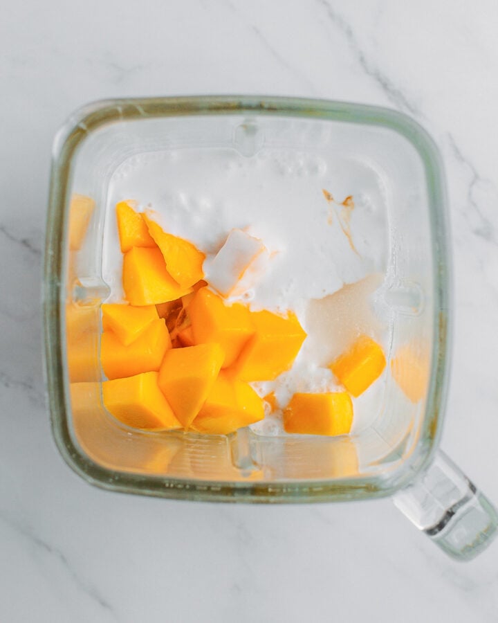 Diced mango and coconut milk in a blender.