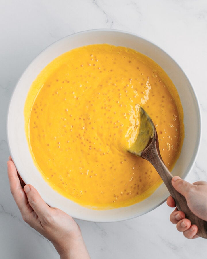 Mixing cooked tapioca pearls with puréed mango in a bowl.