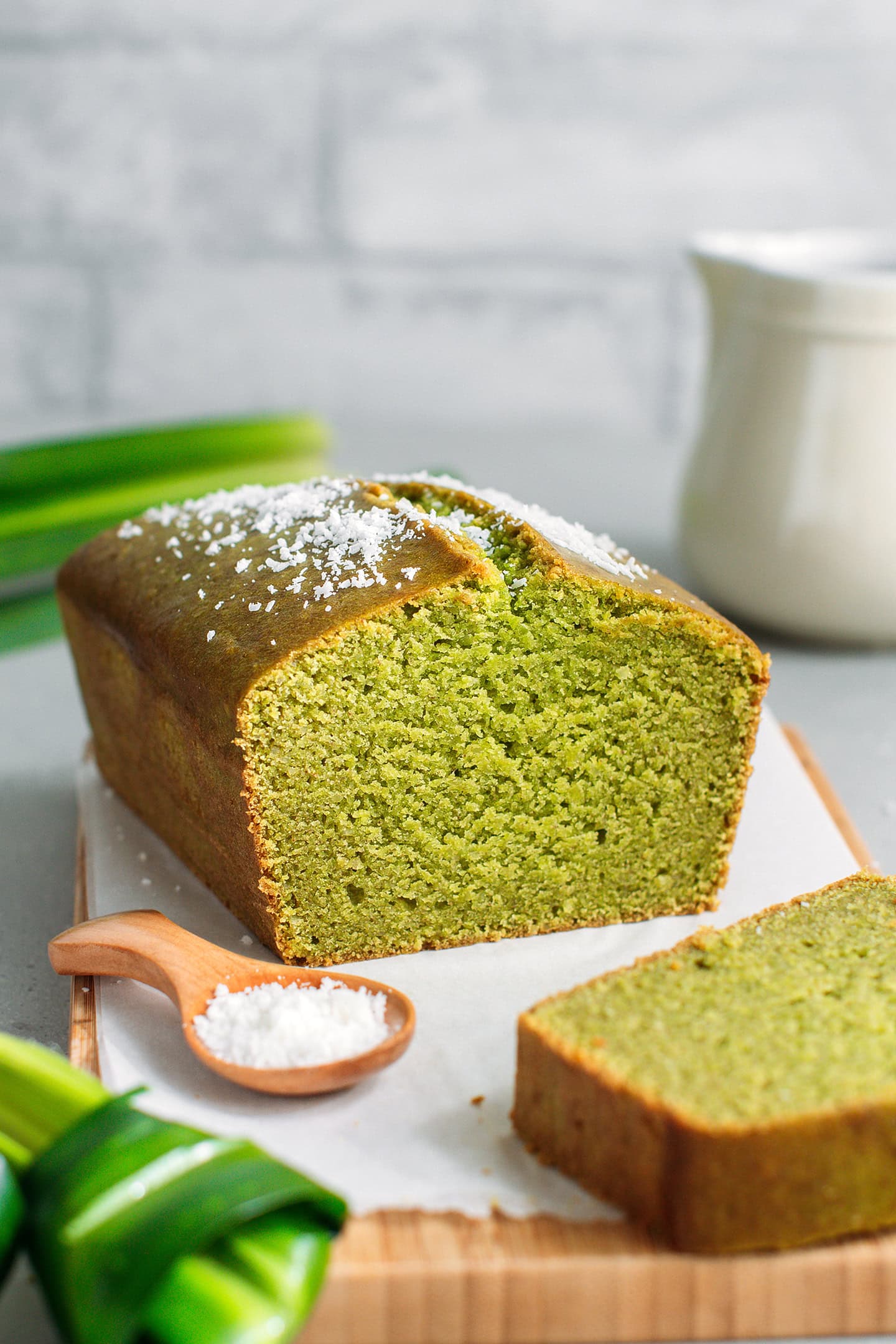 Pandan bread topped with shredded coconut on a wooden board.