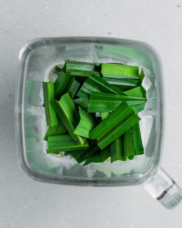 Coconut milk and pandan leaves in a blender.