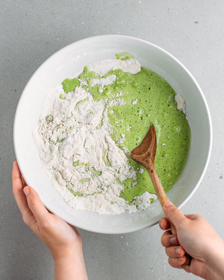 Mixing pandan coconut milk with buckwheat flour and almond flour in a mixing bowl.