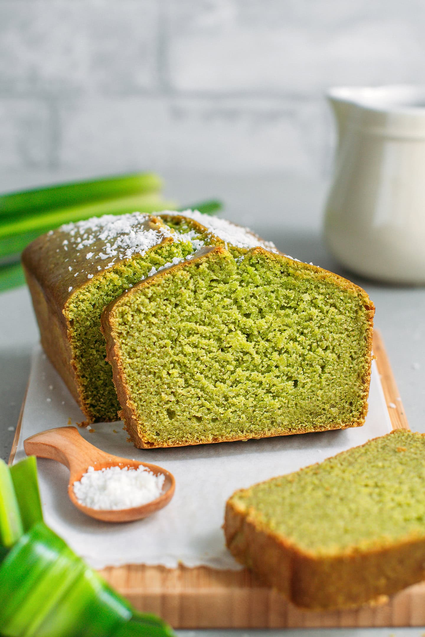 Pandan bread topped with shredded coconut on a wooden board.