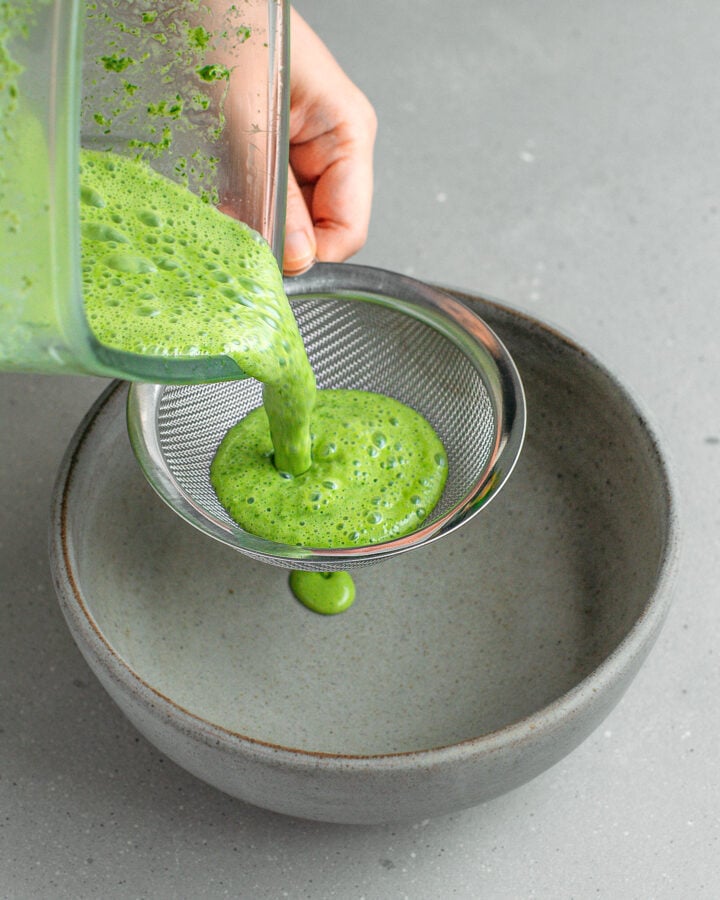 Straining pandan milk through a fine-sieve mesh.