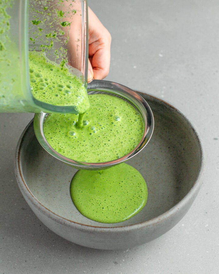 Straining pandan milk through a fine-sieve mesh.