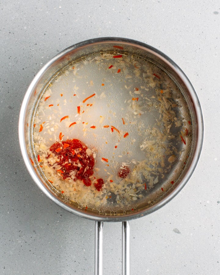 Water, vinegar, sweet chili sauce, and chili in a saucepan.