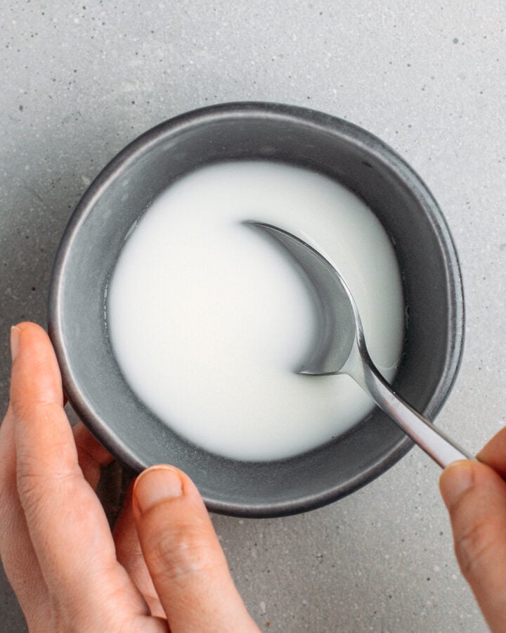 Whisking cornstarch with water in a small bowl.