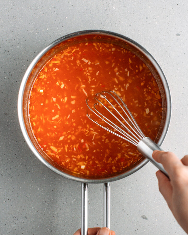 Whisking sweet and sour sauce in a saucepan.