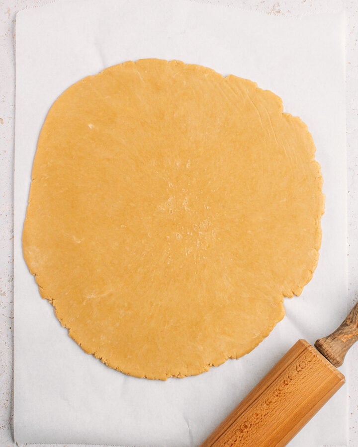 Flattened dough on a layer of parchment paper.