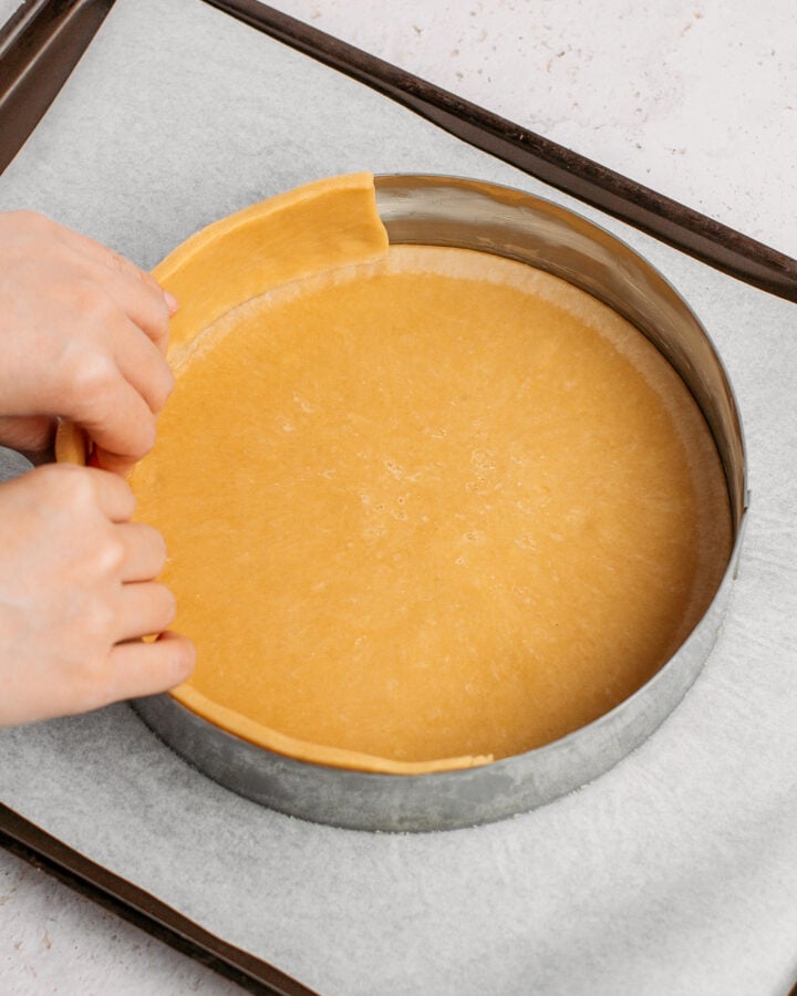 Arranging a strip of pie crust dough inside a metal pastry ring.