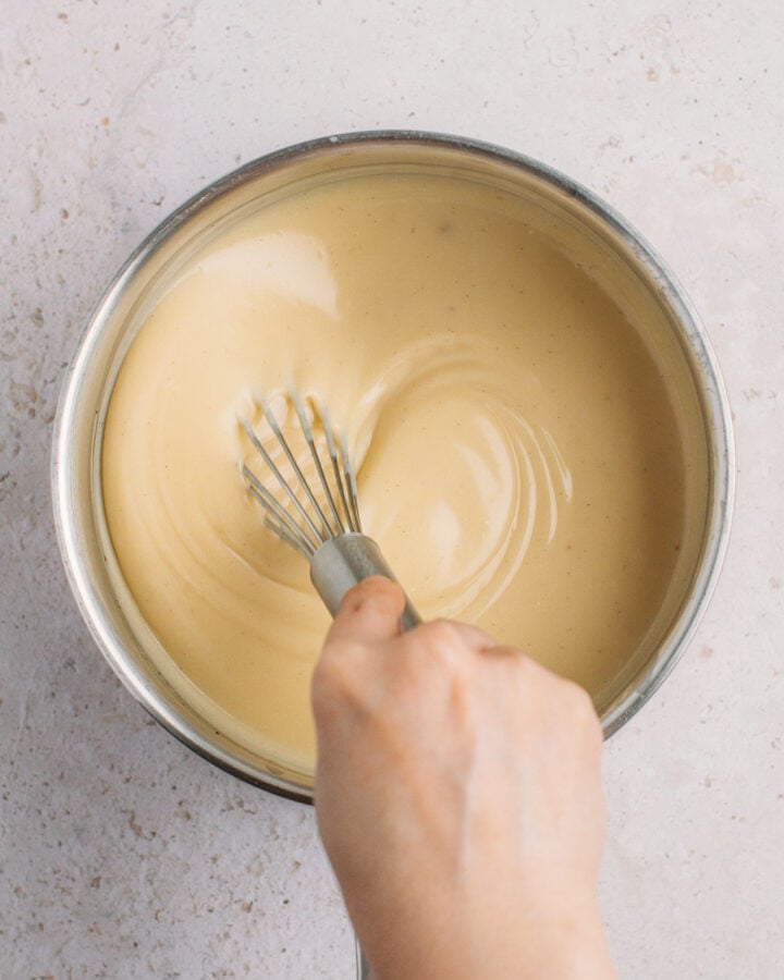 Whisking vanilla custard cream in a saucepan.
