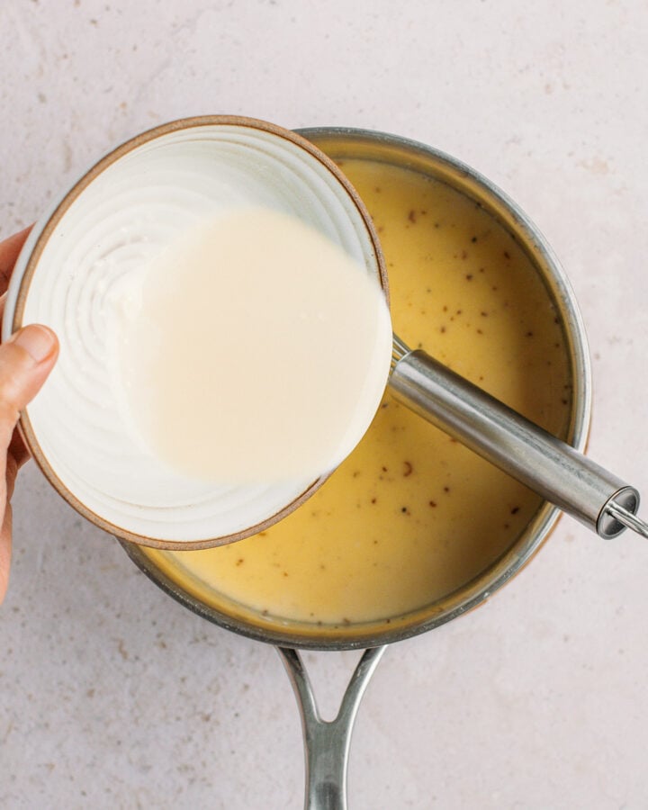 Pouring cornstarch slurry into a saucepan.